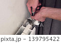 metal wrench clangs and bangs against a metal radiator, rattling as it is adjusted 139795422