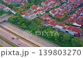Aerial drone footage showing a modern residential housing complex with red-roof houses located alongside a multi-lane highway in Indonesia. 139803270