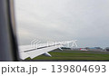 Passenger airplane taking off from Narita International Airport Terminal 1 to Toronto. View of the aircraft wing and airfield infrastructure from a passenger window on a cloudy day. 139804693