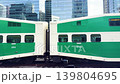 Green double-decker commuter train cars moving past modern glass skyscrapers in downtown Toronto, Canada. Modern city passenger trains arriving at urban public transit station in Toronto, Canada. 139804695