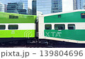 Green double-decker commuter train cars moving past modern glass skyscrapers in downtown Toronto, Canada. Modern city passenger trains arriving at urban public transit station in Toronto, Canada. 139804696