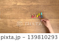 A child places purple clips on a wood-grain desk, silent, in 4K slow motion. 139810293