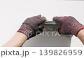 Poor human hands wearing fingerless gloves collecting a large stack of US dollar banknotes. 139826959