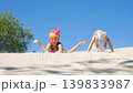 Funny girls are digging in the hot sand on the coast. Girls in swimsuits play together. 139833987