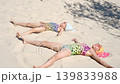 Girls in swimsuits are lying on the hot sand, enjoying the warmth and the sun. Vacation on the coast, sandy beaches 139833988