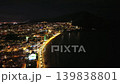 Night aerial beachfront boulevard glowing with street lamps, coastal hotels and restaurants lit along sandy 139838801