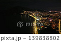 Nighttime illuminated coastline with glowing lights along shore quiet sea, lit promenade and moving cars 139838802