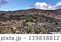 Aerial red cliff with terraced foothills and scrubby vegetation, expansive rocky escarpment against partly 139838812