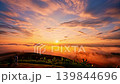 Stunning aerial panorama of Baan Jabo featuring a sea of mist, lush highlands, and tranquil rural life beneath a colorful sunrise sky. Aerial View of  Sun Rays Over Rural Mountain Landscape 139844696