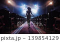 Elegant female silhouette walking toward bright stage lights in cinematic atmosphere 139854129