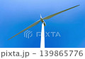 Tall Wind Turbine Against Blue Sky 139865776