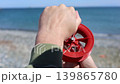 Hands Holding Red Fishing Reel At Sea 139865780