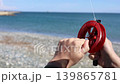 Hands Holding Fishing Reel On Rocky Beach 139865781