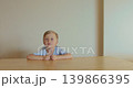 A young boy sits at a table, attentively listening and raising his hands. Learning process, discipline in class. 139866395