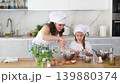 Mom and girl are talking in kitchen and mixing ingredients for pastry in bowl with whisk 139880374