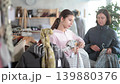 Mother and teen daughter looks at products in store and selects coat or jacket for child 139880376