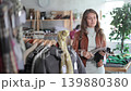 Positive young girl choosing warm glove in clothing shop with new winter collection 139880380