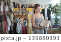 Woman came to a sale in a clothing and accessories store, she is choosing a fashionable bag with interest 139880393