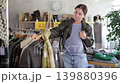 Happy pregnant woman choosing winter coat in clothing shop with large assortment 139880396