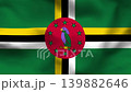 Dominica flag on wavy fabric, top view. Green textile with yellow, black, and white cross and red circle with parrot emblem 139882646