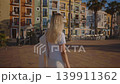 A person strolls through the Villajoyosa coast in Spain. Bright buildings line the streets as the sun shines down. This location is lively and full of charm. Warmth surrounds each step taken. 139911362