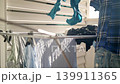 In this cozy setting along the Villajoyosa coast of Spain, a person hangs freshly washed clothes on a drying rack outside. The sun shines bright as items are carefully placed. 139911365