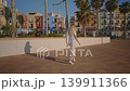 A person walks on the path beside colorful buildings in Villajoyosa, Spain. The bright atmosphere highlights the coastal setting and local life in the area. 139911366