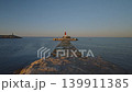 This takes the viewer through the Villajoyosa coast in Spain at sunrise. The video shows a pathway leading to a lighthouse and the clear water around it. 139911385