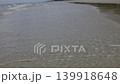 Gentle Ocean Waves Washing Ashore In The Morning Sunlight. Calm turquoise sea water splashing on the sandy beach during early day, suitable for nature relaxation videos or travel advertisements. 139918648