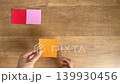 The child's hand places the small origami paper received from Mom's hand as the third piece. 139930456