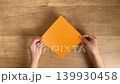 4K slow-motion video of a child's hand placing an orange origami. 139930458