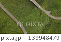 Aerial footage of a curved road and bridge running through a lush, green forest in Minami-Aso, Kumamoto Prefecture. 139948479