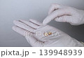 Pediatric dentist in white gloves holding extracted primary milk teeth. Concept of deciduous tooth loss, dental extraction procedure and childhood healthcare. Pediatric dentist in white gloves holding extracted primary milk teeth. Concept of deciduous tooth loss, dental extraction procedure and childhood healthcare. 139948939
