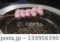 Pink heart-shaped marshmallows on a wooden skewer held over a hot charcoal barbecue grill. Sweet romantic dessert concept for Valentines Day, camping, or a picnic. Soft focused metal grill background. 139956390