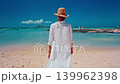 Woman in a hat and long white robe walking toward the ocean in Mauritius 139962398