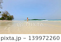 Low flying FPV drone shot of woman running through shallow turquoise water on tropical sandy beach in Thailand during sunny summer vacation. 139972260