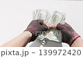 Adult beggar counting fiat cash indoors with fingerless gloves 139972420