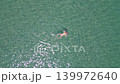 Aerial top down view of woman floating in calm tropical sea with sunlight reflections and clear turquoise water during summer vacation. 139972640
