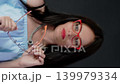 Woman wearing red glasses and holding a second pair of orange spectacles. Choosing between different eyewear styles. 139979334