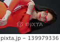 Elegant woman in a red dress and red glasses posing with a white handbag. Fashion and matching style concept. 139979336