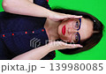 Confident woman in glasses looking seriously at the camera on a green background. Business portrait of a teacher or secretary. 139980085