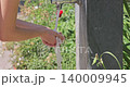Woman refreshing face with water from public fountain 140009945