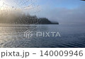 Spiderweb with glistening dew drops at foggy morning lake 140009946
