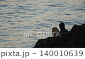 Shaman drumming ocean silhouette during mystic sunset ritual on rocks by the flowing water for spiritual meditation. 140010639
