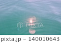 Sunlight reflection water ripples on the turquoise surface of a calm ocean creating a serene atmosphere with bright glares and lens flares 140010643