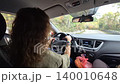 Driving, road trip, woman, maneuvering vehicle on an autumn road winding through green mountain forest during vacation travel. 140010648