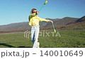 Juggling, gymnastics, mountain. Young girl practicing rhythmic sport with clubs on green field under a clear blue sky with beautiful peaks. 140010649