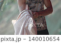 Man, packing, yoga mat, male athlete puts pink mat into beige bag outdoors. 140010654