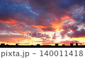 The sun sets behind a city skyline, creating bright colors in the clouds. The frames show the changing sky as the day turns to night over buildings and rooftops 140011418