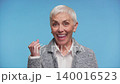 Happy senior woman celebrating success on blue background 140016523